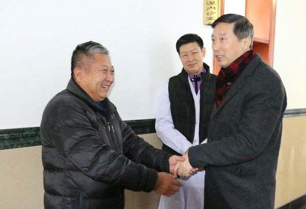 党委书记丁国旭与黑龙江日报社驻齐记者站站长姚建平亲切握手